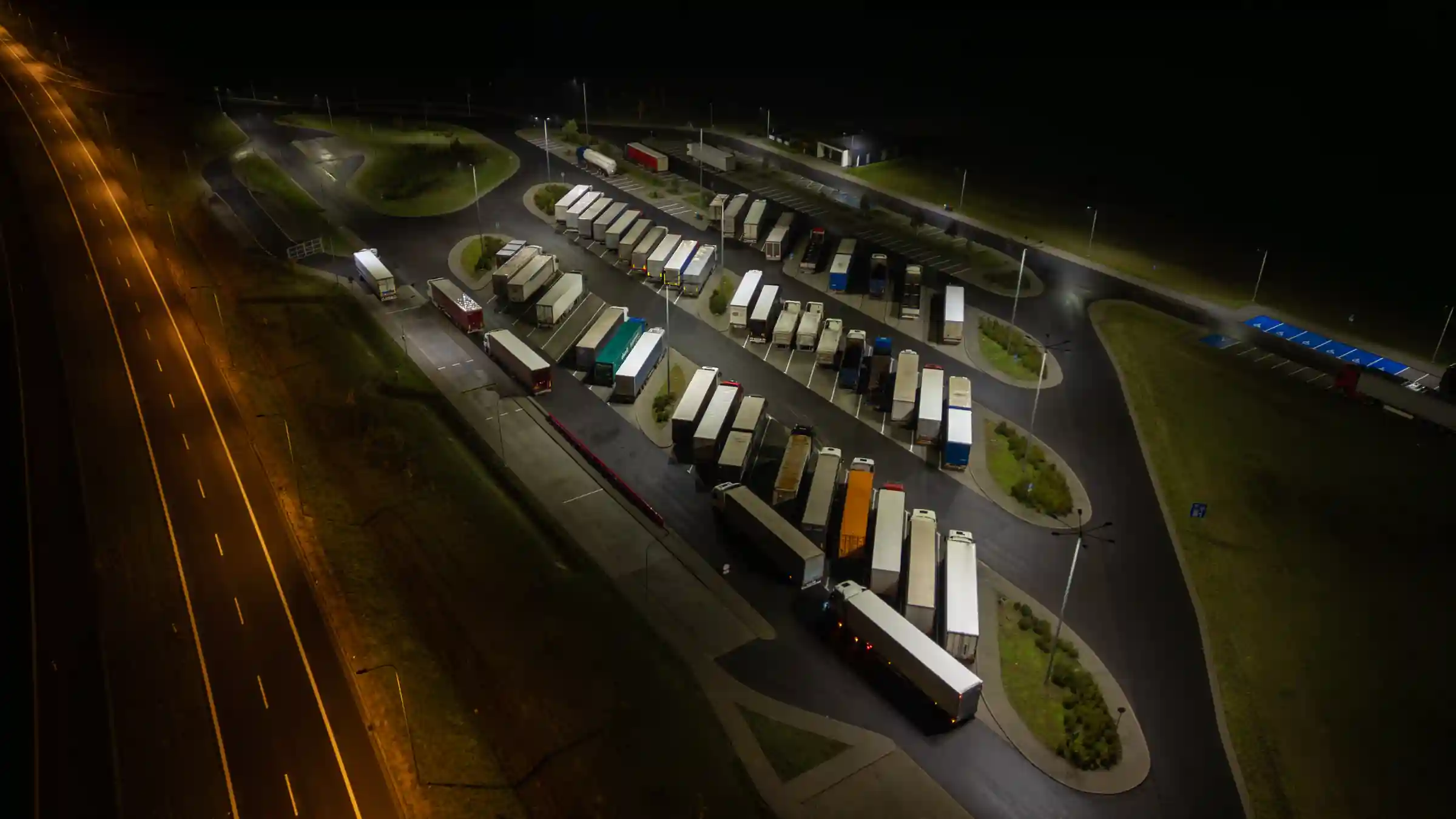 n3-flotas-1-playa-camiones-noche Vista aérea nocturna de camiones de carga estacionados en una playa junto a la ruta
