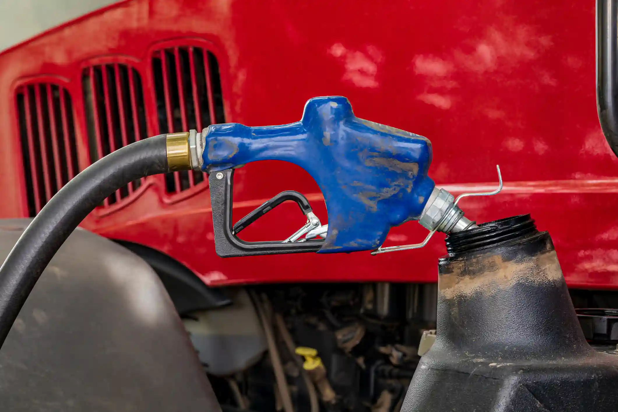 Pico de surtidor diesel azul cargando combustible en un tractor rojo